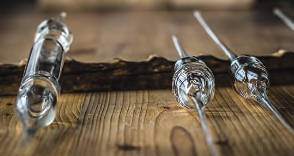 Close-up image of several traditional glass beer hydrometers lying on a wooden surface. The wooden background has a rustic texture, adding to the vintage feel of the scene.